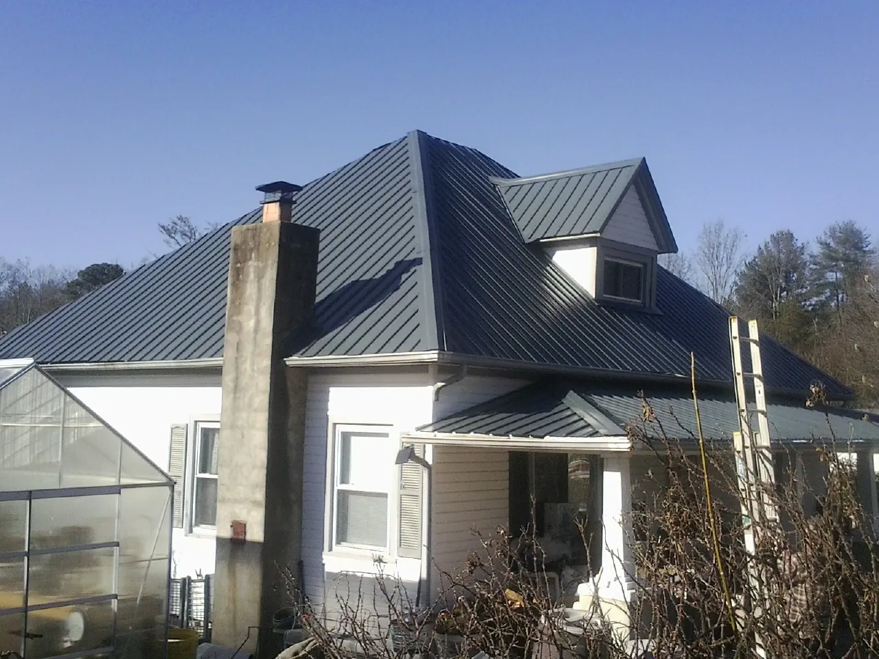 Dark blue standing seam metal roof on a white farmhouse with dormer — Slate & Tile Roof Repair by Roofing Brothers in East Waterboro