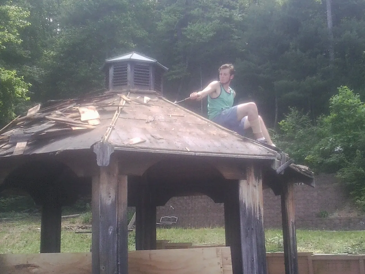 Tearing the old roof off a wooden gazebo before new shakes in East Waterboro