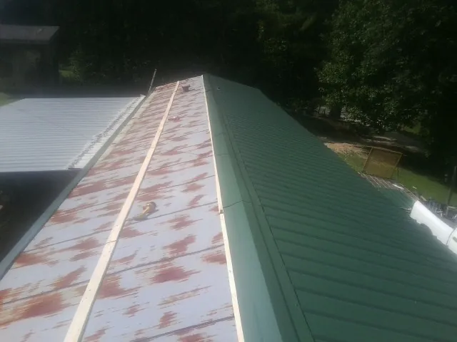Old rusted panels beside newly installed green metal roofing — Wind Damage Roof Repair by Roofing Brothers in East Waterboro