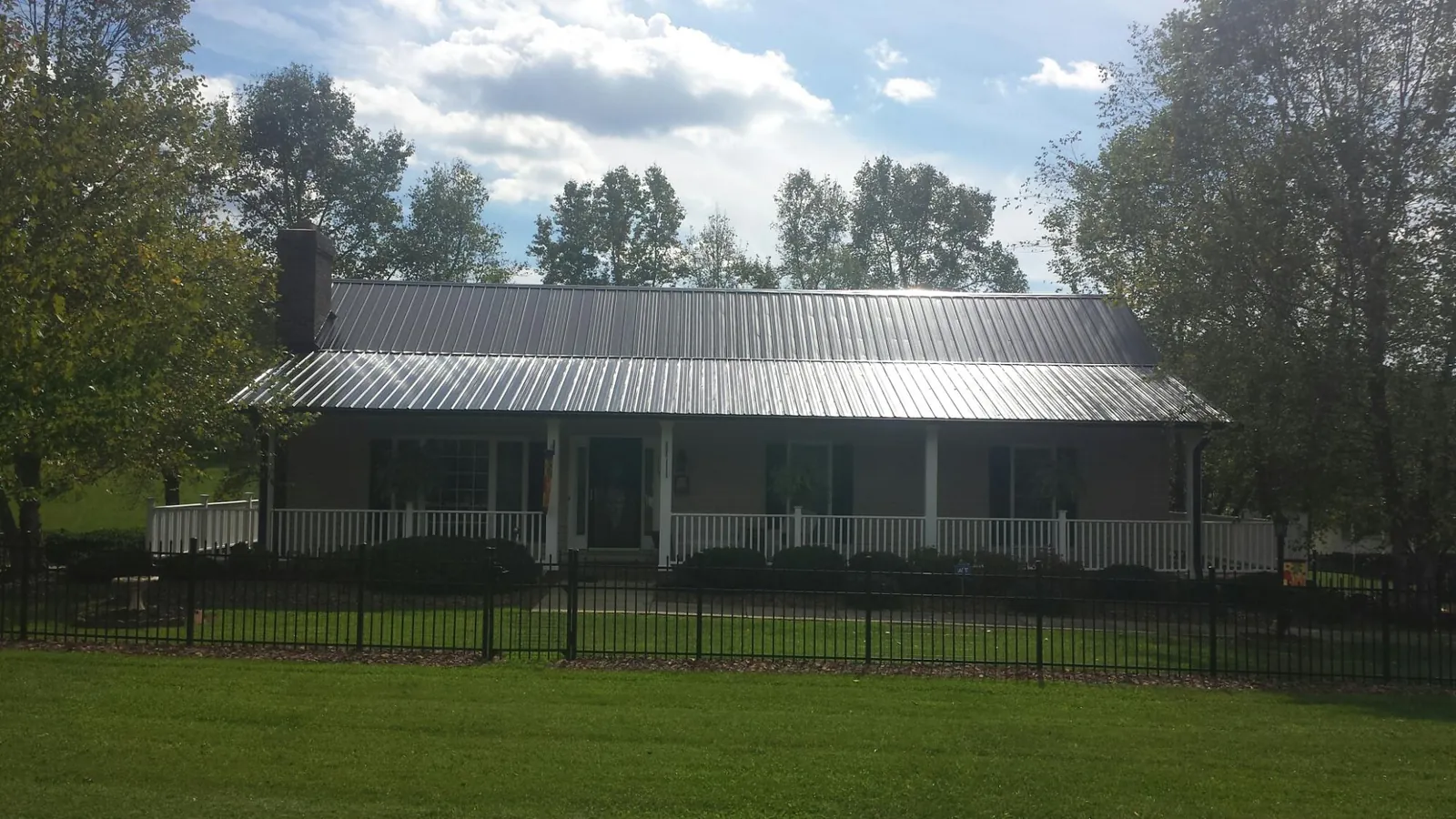 Gray metal roof on a brick ranch with a full width front porch — Gutter Guard Installation work by our crew in East Waterboro