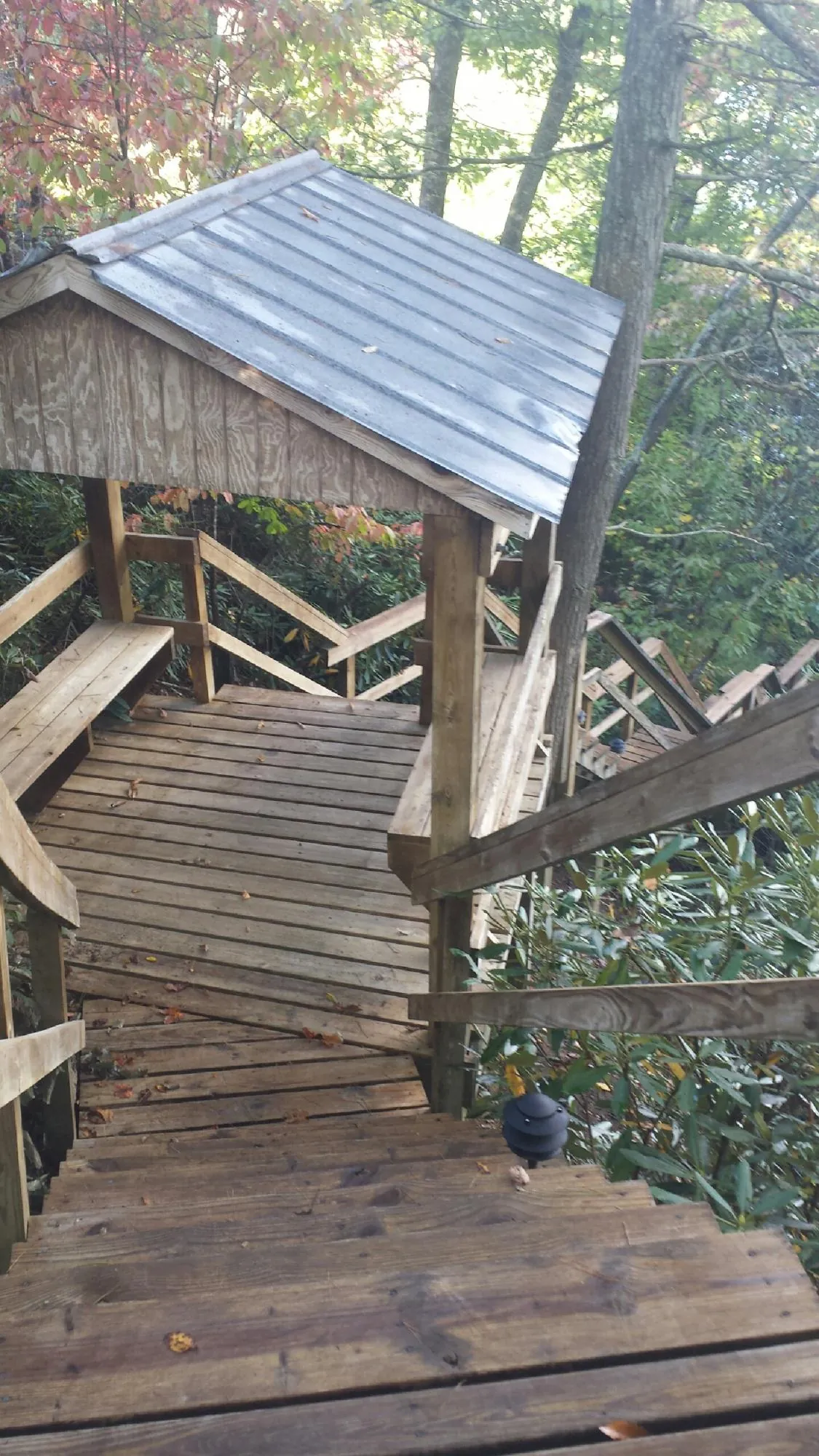 Metal roofed shelter over wooden steps on a wooded walkway — Skylight Repair & Installation work by our crew in East Waterboro