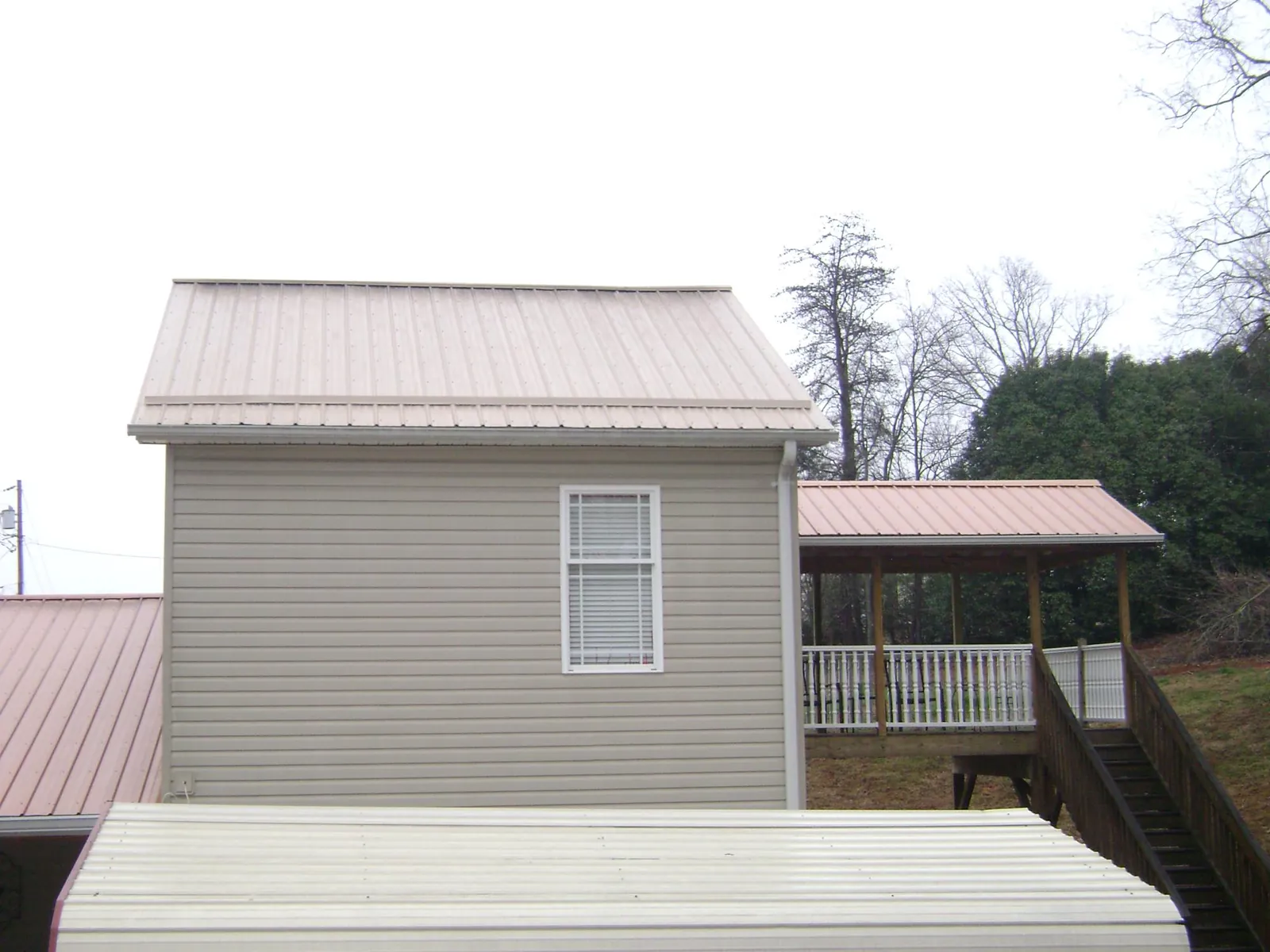 Tan metal roofs on a two story addition and attached porch, from a Roof Replacement job in East Waterboro