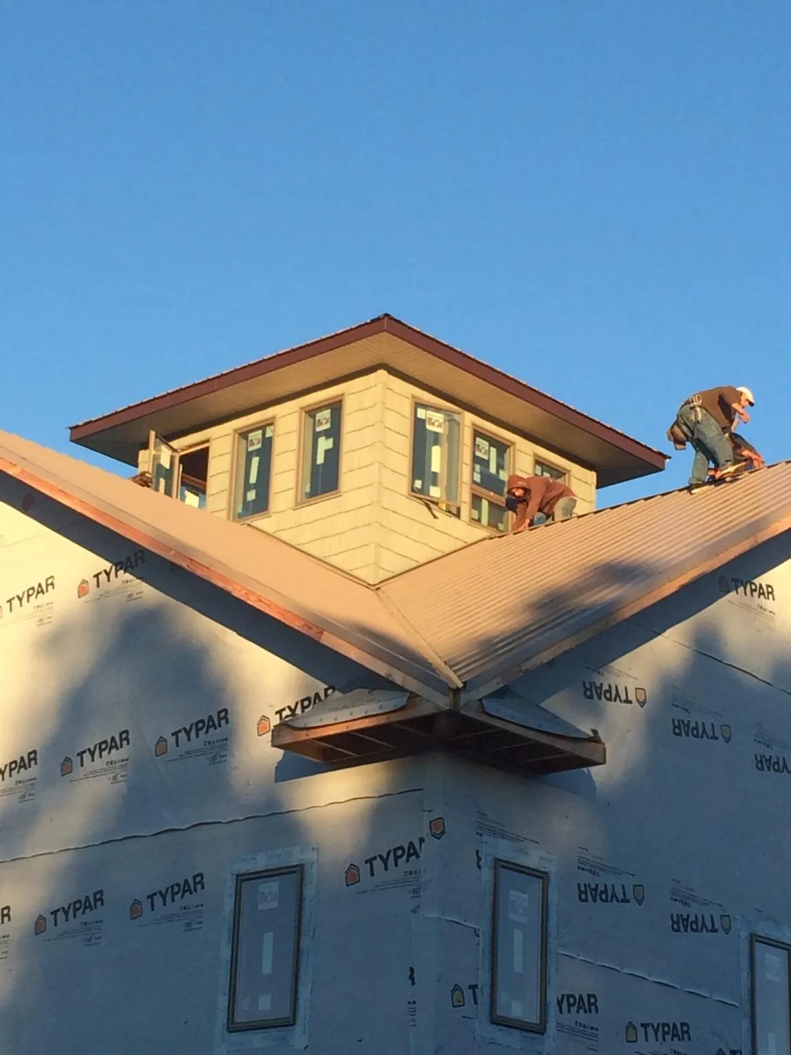 Roofers working around a rooftop cupola on a new metal roof at sunset — Roof Waterproofing in East Waterboro by Roofing Brothers